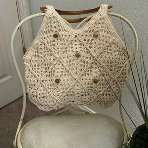 Cream macrame handbags with wood-like handles.